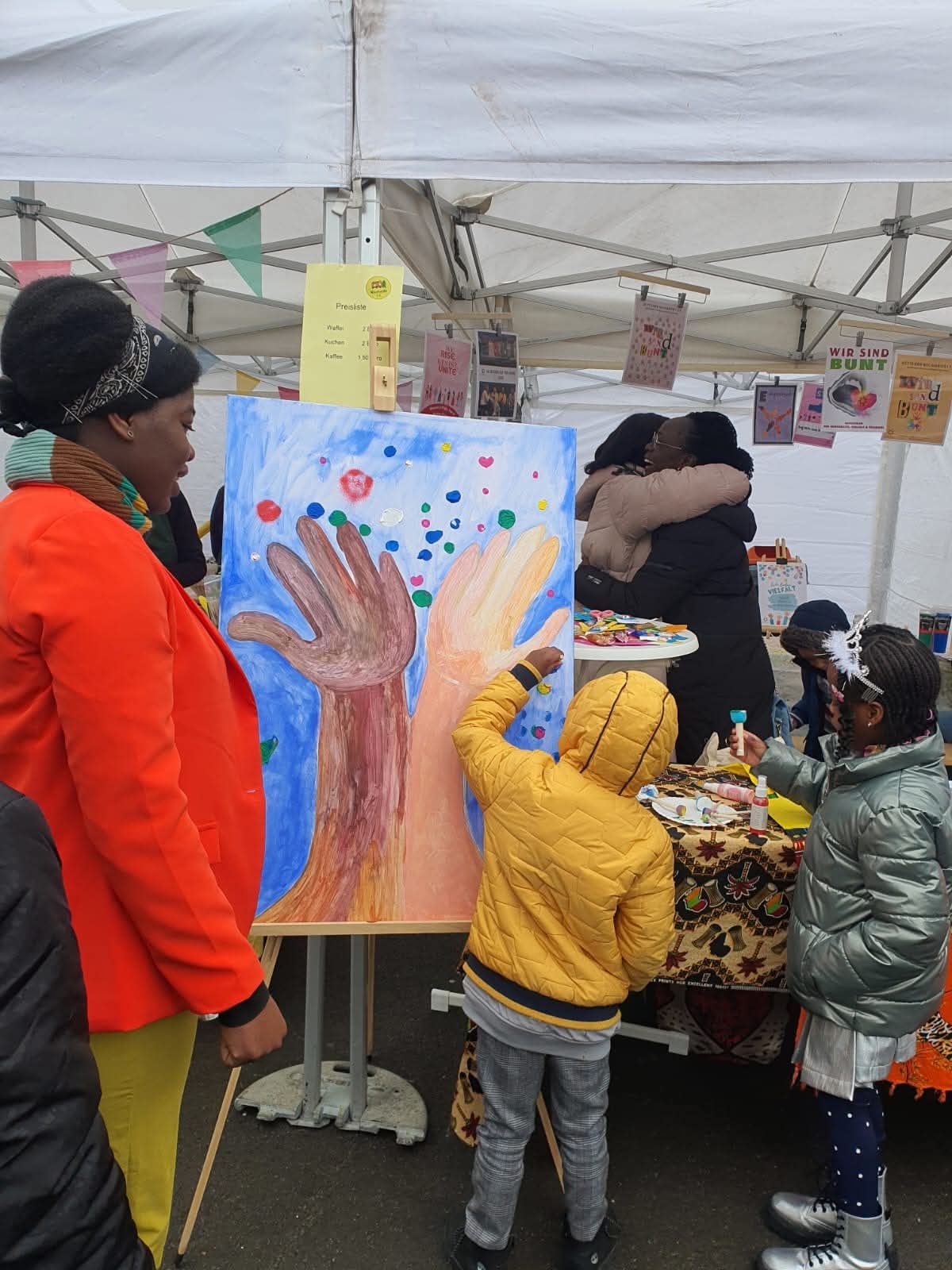 Kinder malen ein gemeinsames Hände-Kunstwerk am Stand der Kette der Solidarität e.V. beim Friedensfest