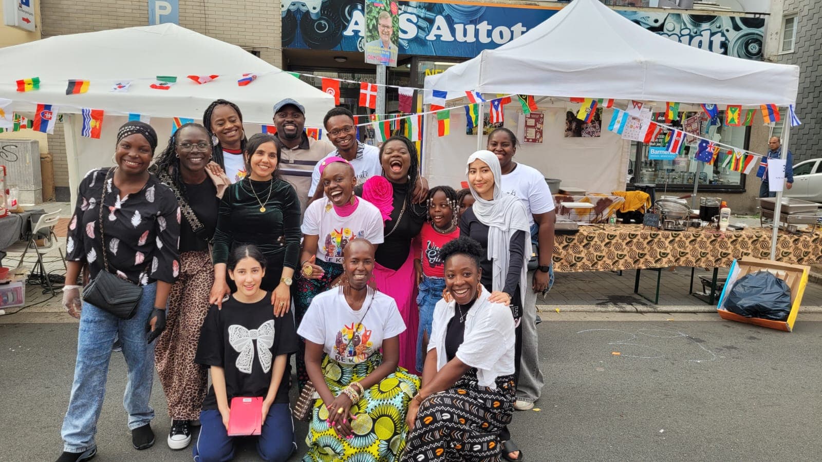 Großes Gruppenbild des Teams der Kette der Solidarität e.V. am eigenen Stand beim ersten Bürgerfest — Pavillons, Länderflaggen und viele Menschen aus mehreren Nationen