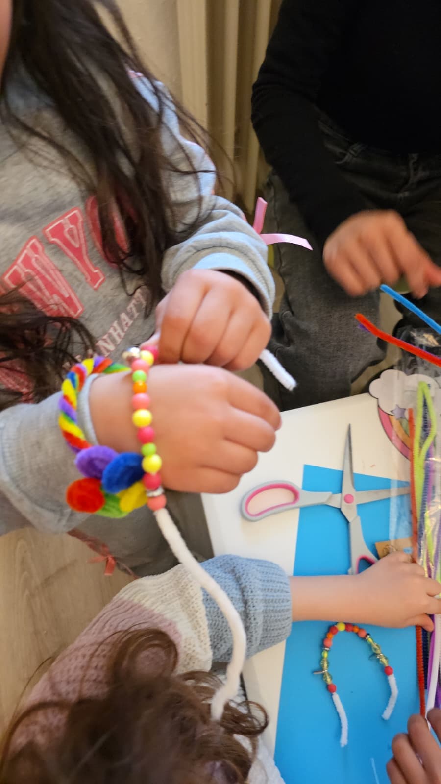 Kinder fädeln bunten Perlenschmuck in der Kreativwerkstatt der Kette der Solidarität e.V.