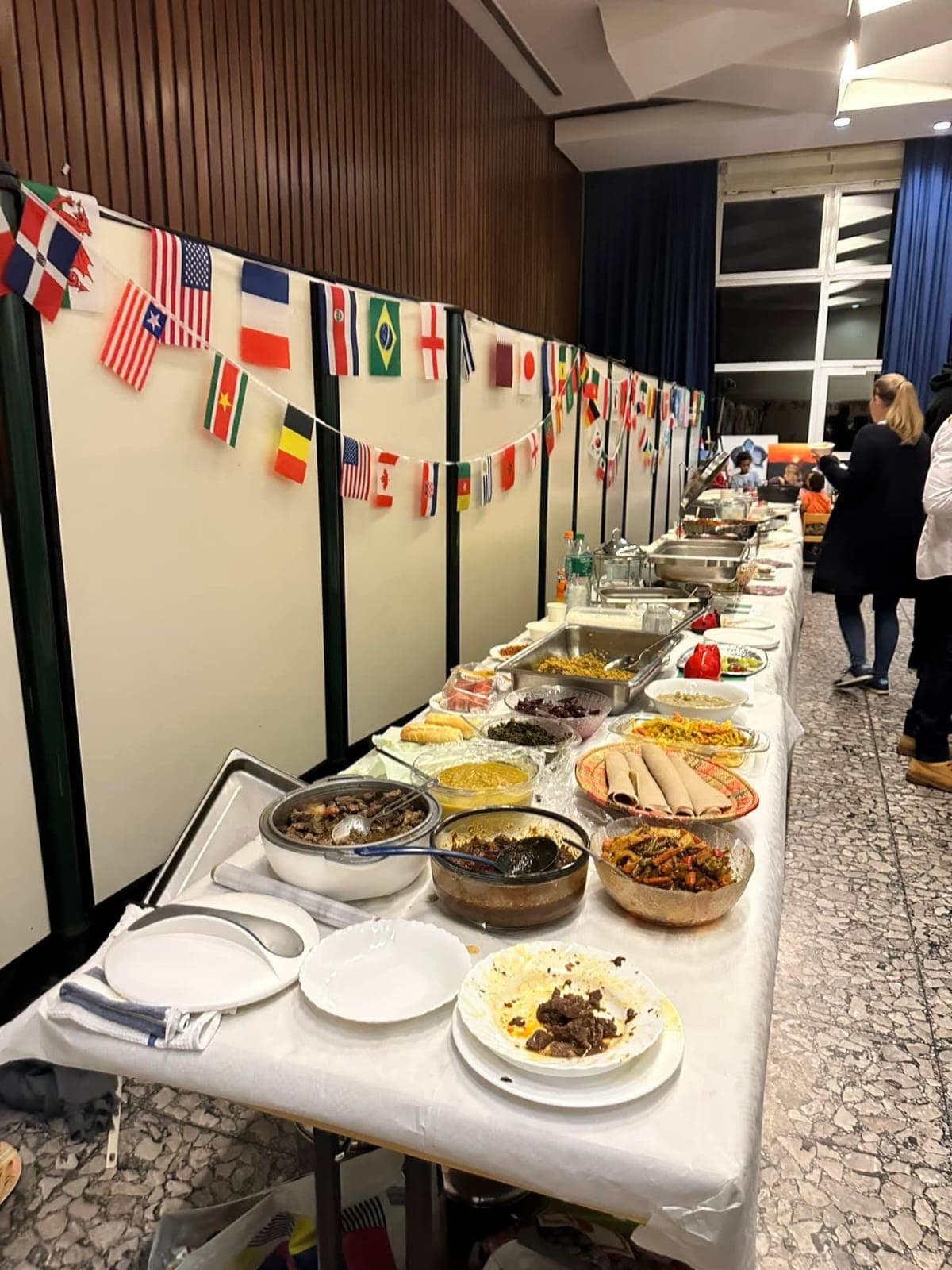 Langes internationales Buffet unter Länderflaggen — All Nations auf der Bühne
