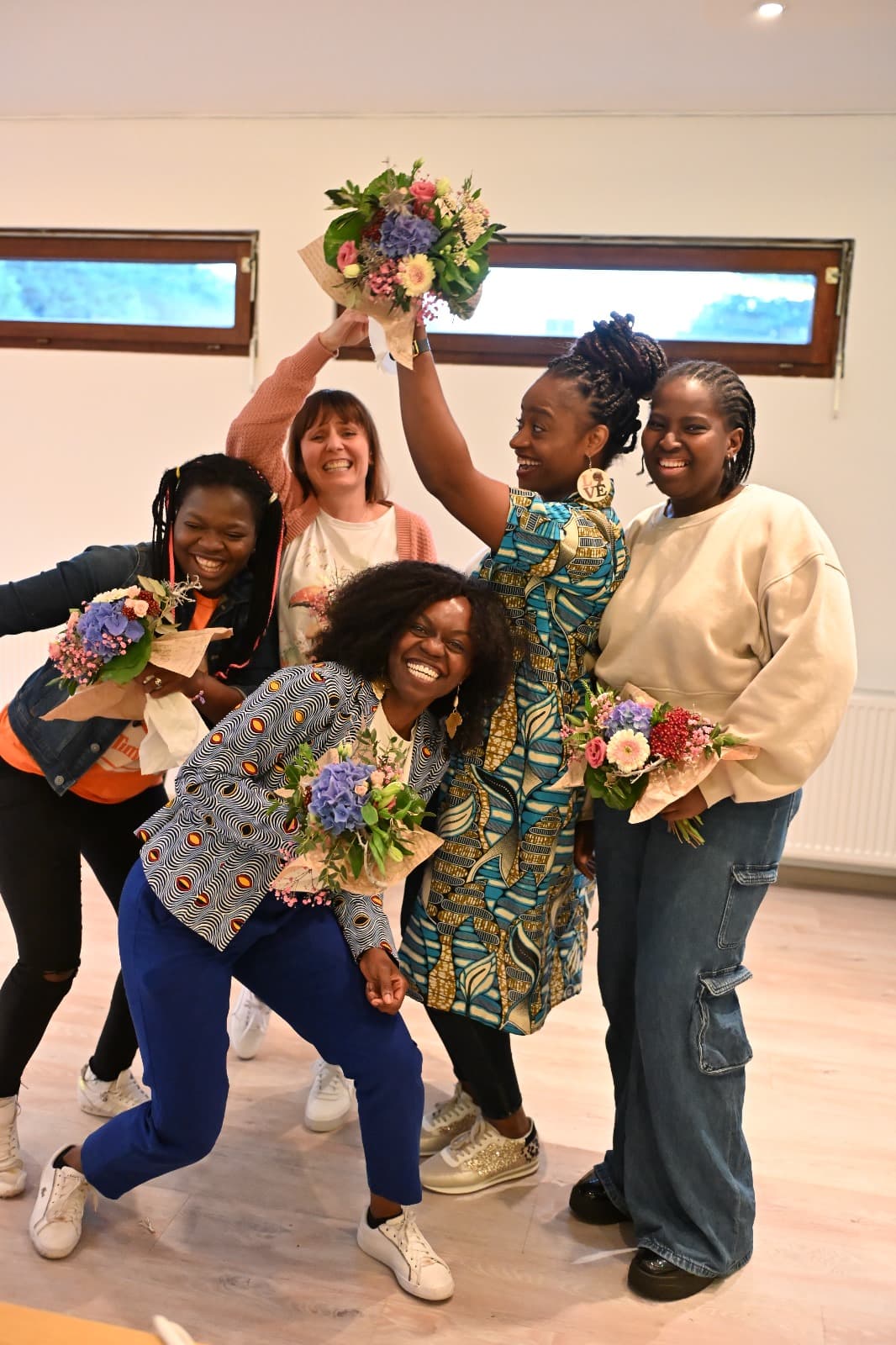 Fröhliche Runde von Frauen mit Blumen beim Empowerment-Workshop der Kette der Solidarität e.V.
