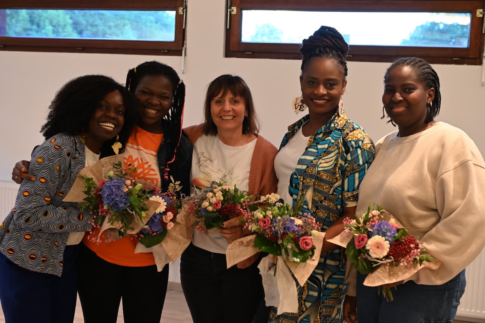 Frauen mit Blumensträußen lächeln beim Empowerment-Workshop „Was uns empowert?“